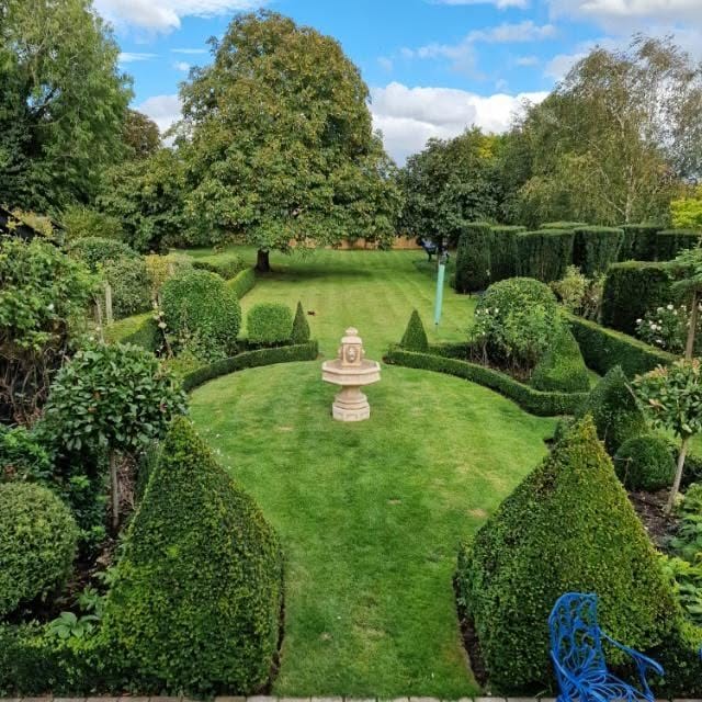 Beautifully maintained formal garden with clipped topiary and a stone fountain