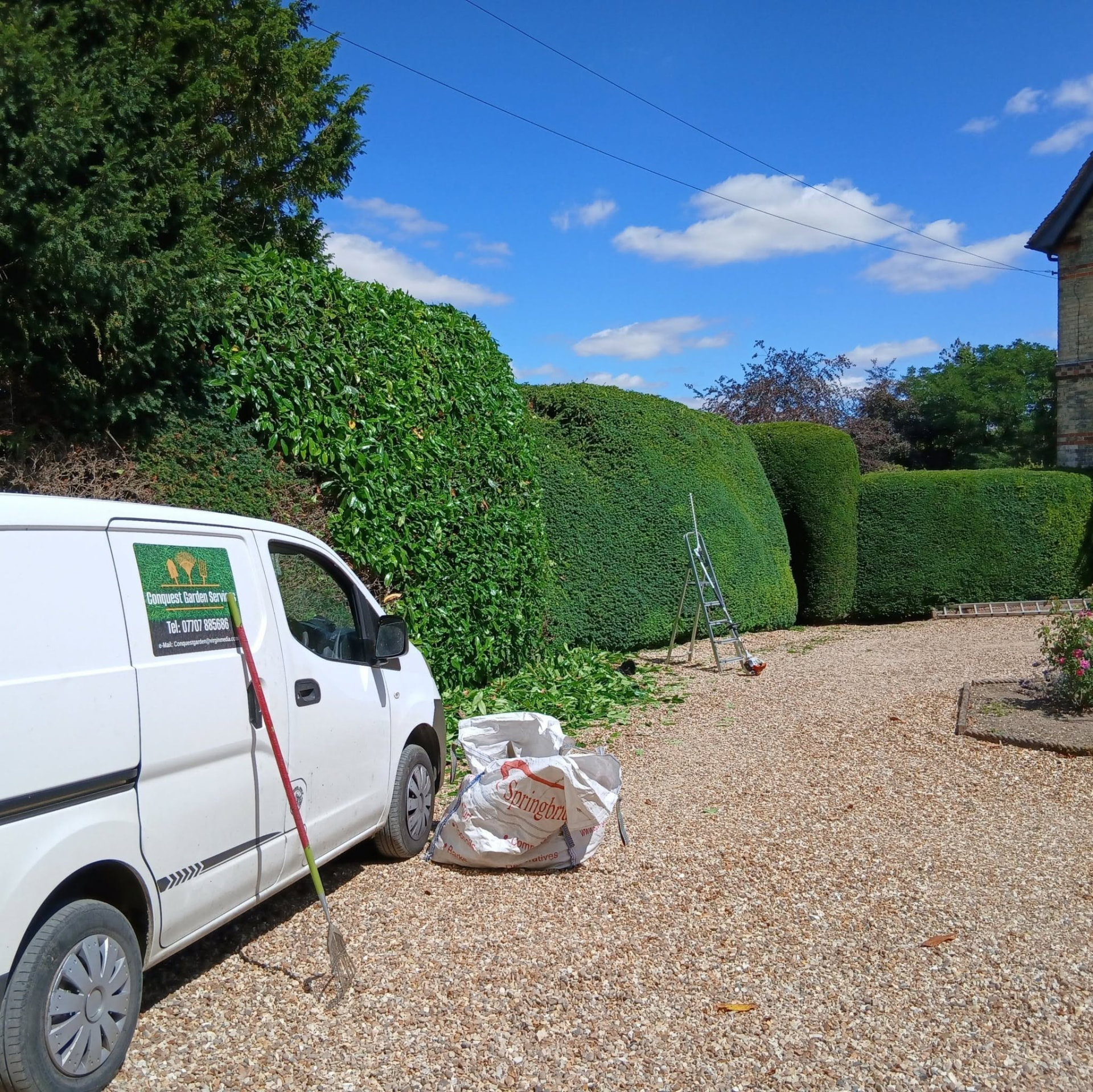 The Conquest Garden Services van beside neatly clipped hedges